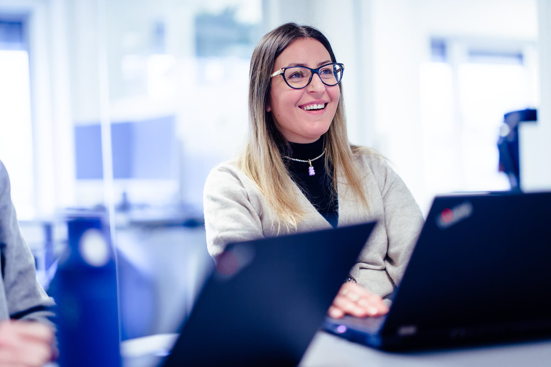 Image of a smilling woman sitting in front of the laptop to illustrate contact us page